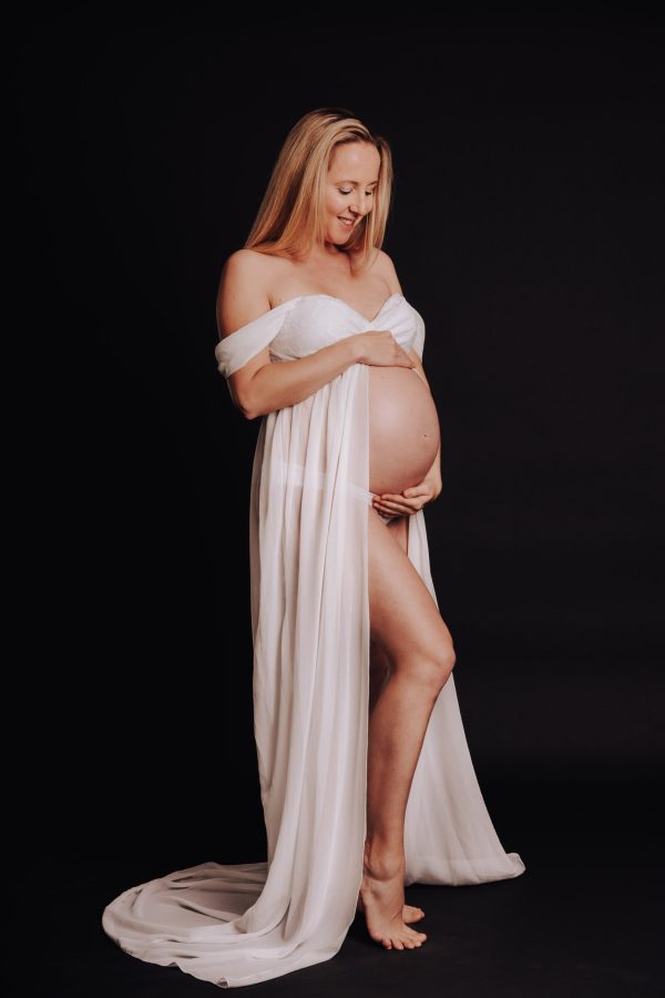 Schwangere blonde Frau, in weissem Kleid speziell für Babybelly. Studioaufnahme LowKey